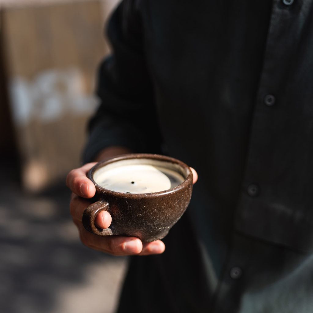 Person hält einen Kaffeeform Cup mit einem schwarzen Kaffee