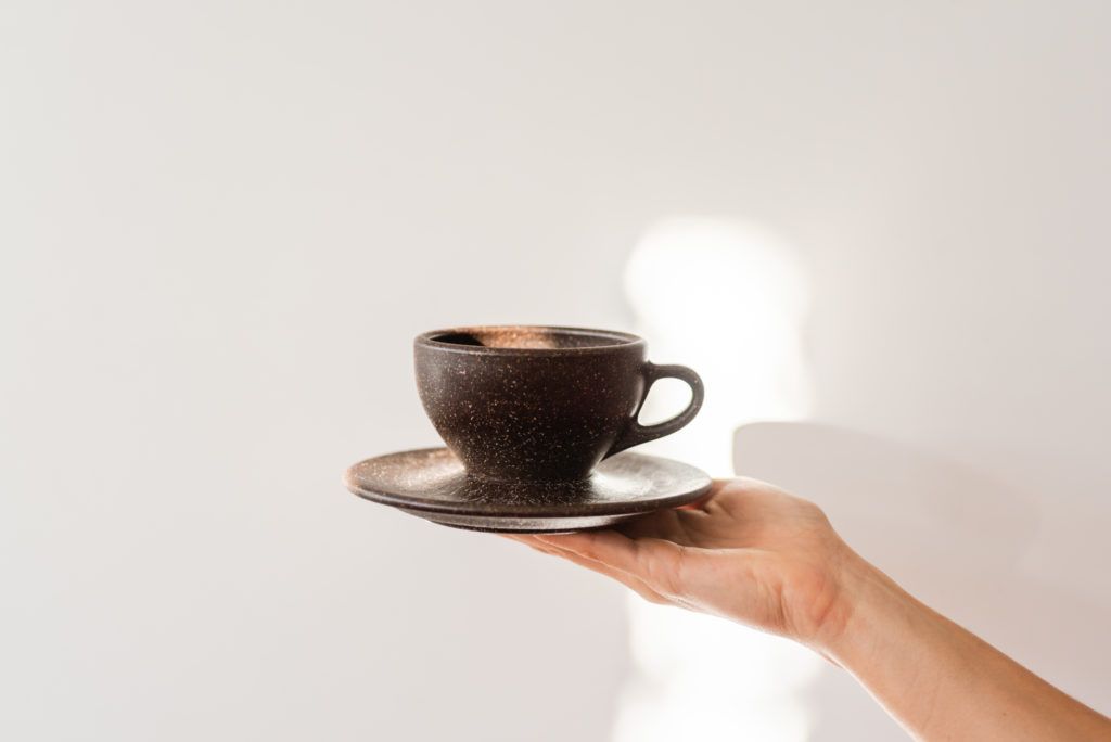 Hand hält Kaffeeform Espresso Cup vor einem weißem Hintergrund