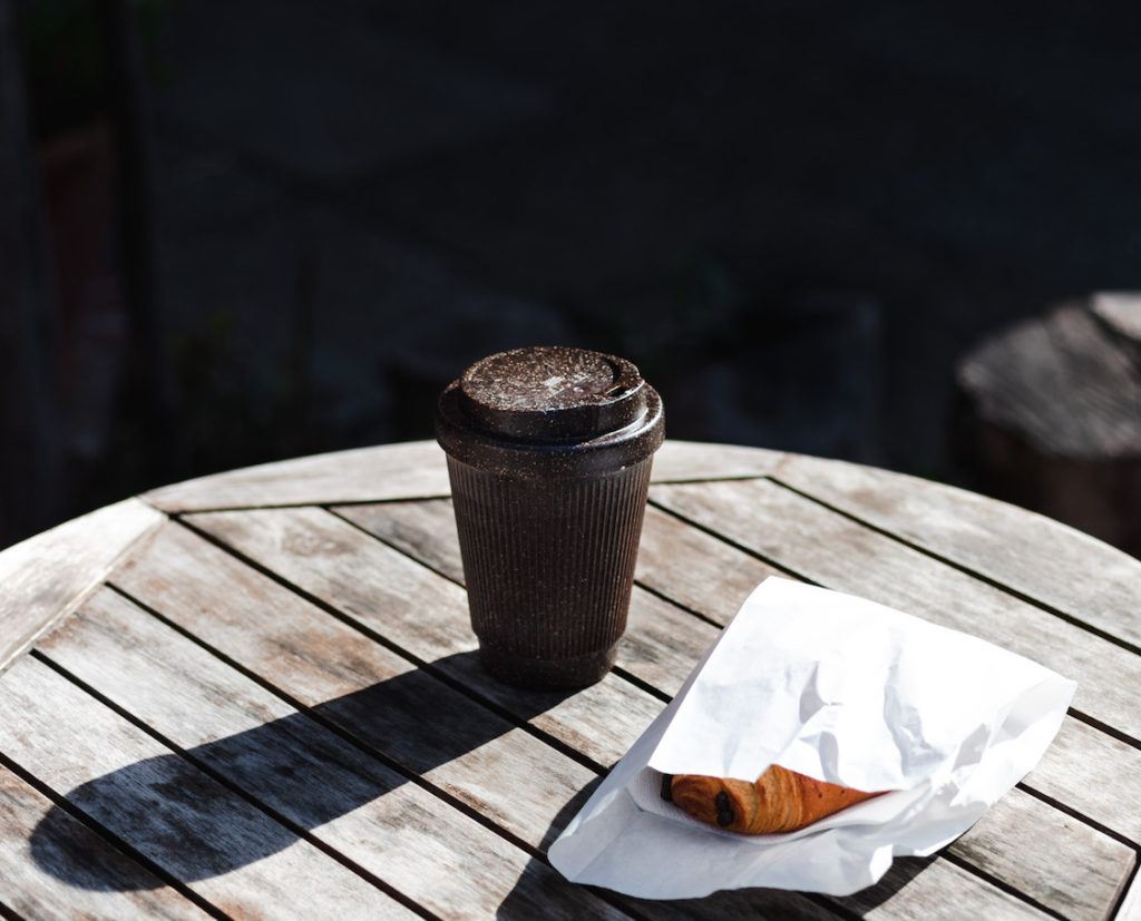 Kaffeeform Weducer Cup mit Gebäck auf einem Holztisch