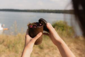 Person hält einen Weducer Cup gefüllt mit Kirschen in der Natur