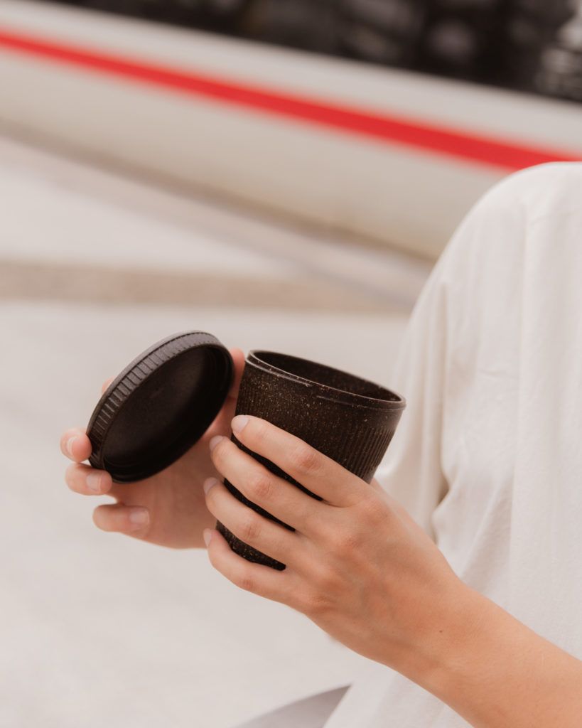 Person hält den Kaffeeform Weducer Cup mit dem Weducer Cap vor einem neutralen Hintergrund