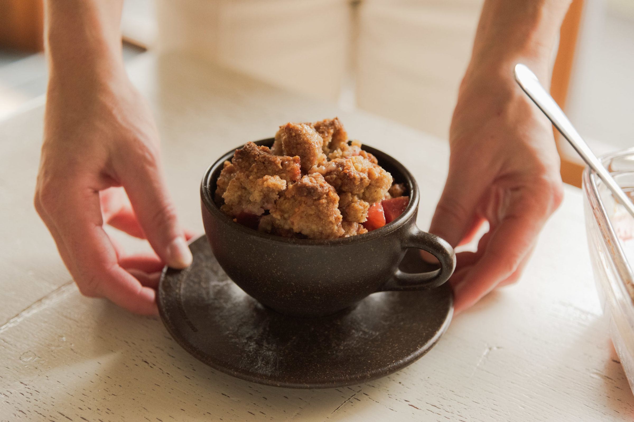 Hand hält einen Kaffeeform Cup gefüllt mit Apfel Crumble