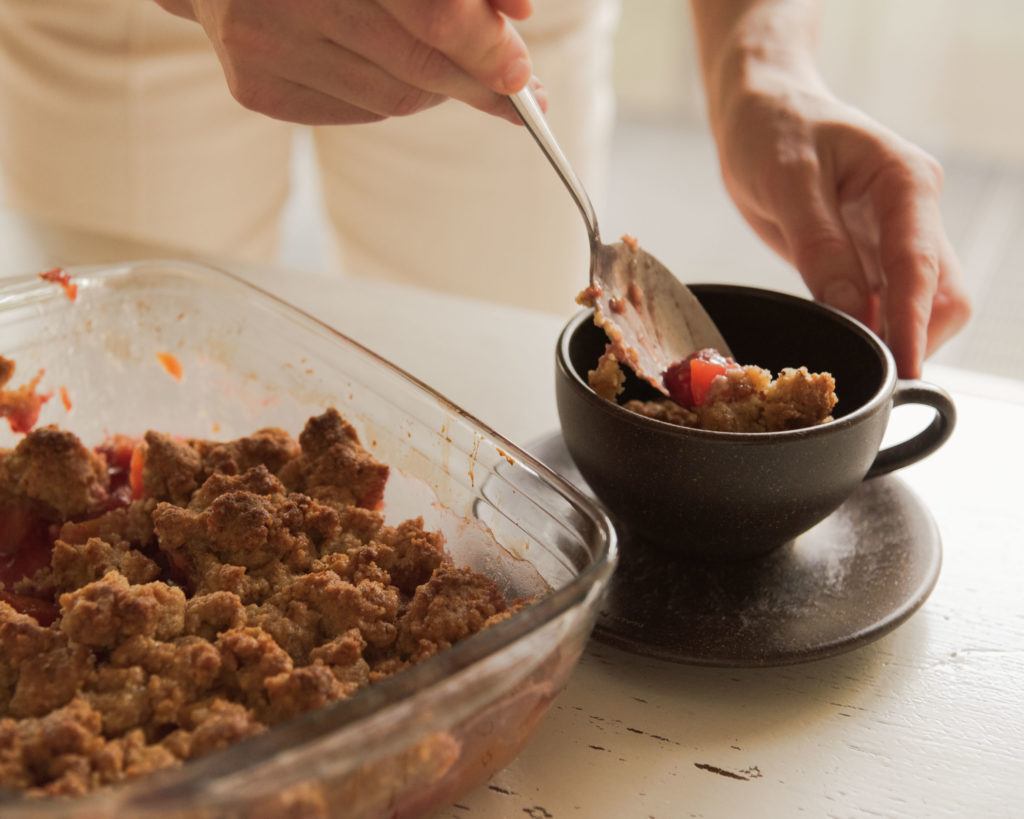 Person löffelt Apfel Crumble in einen Kaffeeform Cup