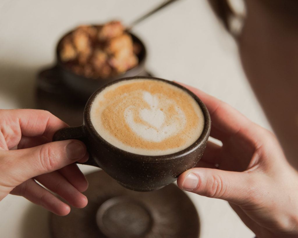 Person trink einen Cappuccino aus einem Kaffeeform Cup