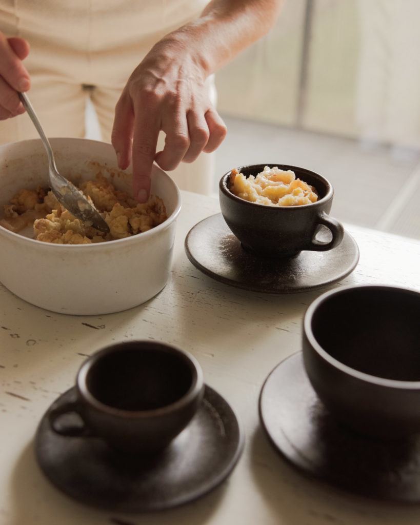 Person bereitet Crumble zu an einem Tisch mit Kaffeeform Cups